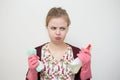 Unhappy sad young caucasian girl woman with rubber gloves, sponge and sprayer, cleaning the house
