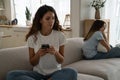 Unhappy sad young caucasian mother and teenage daughter sitting separately on sofa after quarrel Royalty Free Stock Photo