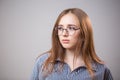 Unhappy, sad young student girl with glasses looking away on grey background with copyspace Royalty Free Stock Photo