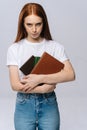 Unhappy sad young woman college student holding book and looking at camera on isolated background. Royalty Free Stock Photo