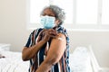 Unhappy senior african american woman wearing face mask with plaster on arm after vaccination Royalty Free Stock Photo