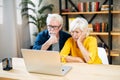 Unhappy senior couple looks at laptop screen