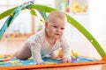 Unhappy seven months baby girl crawling on colorful playmat Royalty Free Stock Photo