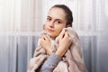 Unhappy sick brunette girl wrapped in blanket suffering from cold at home, looking at camera, freezing, complaining to