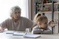 Unhappy grandmother and small granddaughter have fight doing homework