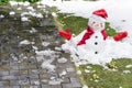 Unhappy snowman in mittens, red scarf and cap is melting  outdoors in sunlight on snowy green grass with small yellow flowers Royalty Free Stock Photo