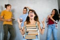 Unhappy student girl looking at her lazy mates who are playing with the phone instead of working