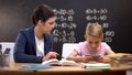 Unhappy teacher trying to explain task to boy playing on smartphone, disrespect Royalty Free Stock Photo