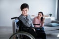 Unhappy teen boy in wheelchair having conflict with his mother, listening to her scolding at home. Relationship problems