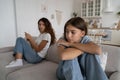 Offended teen girl feeling sad after argument with parent, sitting separately with mother on sofa Royalty Free Stock Photo