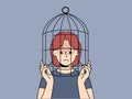 Unhappy teen girl with head in birdcage