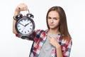 Unhappy teen girl holding big alarm clock pulling discontent face