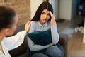 Unhappy teen lady having problem, hugging pillow and talking with friend who showing compassion and trying to appease