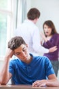 Unhappy Teenage Boy With Parents Arguing In Background Royalty Free Stock Photo