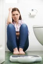 Unhappy Teenage Girl Looking At Bathroom Scales Royalty Free Stock Photo