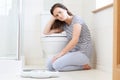 Unhappy Teenage Girl Sitting On Floor With Bathroom Scales Royalty Free Stock Photo