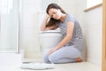 Unhappy Teenage Girl Sitting On Floor Looking At Bathroom Scales Royalty Free Stock Photo