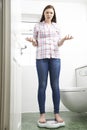 Unhappy Teenage Girl Standing On Bathroom Scales Royalty Free Stock Photo