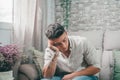 Unhappy teenager feeling bad and sad at home alone thinking about problems. Male depressed person sitting on the sofa Royalty Free Stock Photo