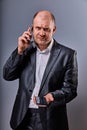 Unhappy tired angry business man talking on mobile phone and holding in hand one more phone in office suit on grey studio Royalty Free Stock Photo