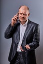 Unhappy tired angry business man talking on mobile phone and holding in hand one more phone in office suit on grey studio Royalty Free Stock Photo