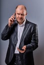 Unhappy tired angry business man talking on mobile phone and holding in hand one more phone in office suit on grey studio Royalty Free Stock Photo