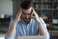 Unhappy tired businessman touching temples, working on difficult task