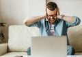 Unhappy tired business man in stress at home office working on computer