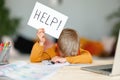 Unhappy tired child  boy student holds a sign HELP while doing homework at home Royalty Free Stock Photo