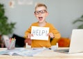 Unhappy tired child  boy student holds a sign HELP while doing homework at home Royalty Free Stock Photo