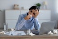 Unhappy tired sad young indian woman suffering from disease and wiping her nose with napkin in workplace