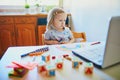 Unhappy and tired toddler girl in front of laptop