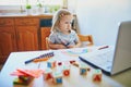 Unhappy and tired toddler girl in front of laptop