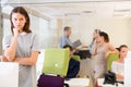 Unhappy tired young businesswoman foreground in busy open plan office Royalty Free Stock Photo