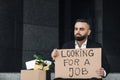 Unhappy unemployed man holding cardboard sign with Looking For a Job written text Royalty Free Stock Photo