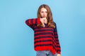 Unhappy unsatisfied young woman wearing striped casual style sweater showing thumbs down, dislike