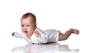 Unhappy upset infant baby boy toddler in diaper and white bodysuit is lying on floor on his stomach and crying Royalty Free Stock Photo