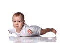 Unhappy upset infant baby boy toddler in diaper and white bodysuit is lying on floor on his stomach and going to cry Royalty Free Stock Photo