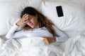 Unhappy woman feeling headache after sudden awakening by phone call