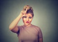 Unhappy woman giving loser sign on forehead, looking at you, disgust on face