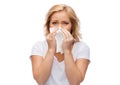 Unhappy woman with paper napkin blowing nose