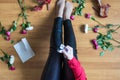 Unhappy woman sitting on the floor among scattered flowers and reading letter. Broken relationships in bad Valentine`s day