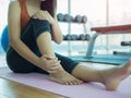 Unhappy woman sitting on the yoga mat with ankle injury