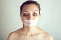 Unhappy woman with wrapping her mouth by adhesive tape painted smile