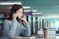 Unhappy young asian woman talking on mobile phone while reading book in library Royalty Free Stock Photo