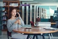 Unhappy young asian woman talking on mobile phone while reading book in library Royalty Free Stock Photo