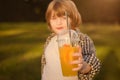 unhappy young boy holding plastic glass with orange juice or smoothie in park outdoors Royalty Free Stock Photo