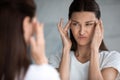 Unhappy young brunette woman dissatisfied with first wrinkles. Royalty Free Stock Photo