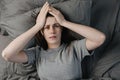 Unhappy young brunette woman lying in bed, look at camera, touching temples close up, tired female suffering from headache Royalty Free Stock Photo