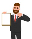 Unhappy young businessman showing blank clipboard and making thumb down gesture sign. Person holding notepad. Male character.